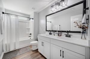 bathroom with wood finished floors, double vanity, shower / bath combo, a sink, and toilet