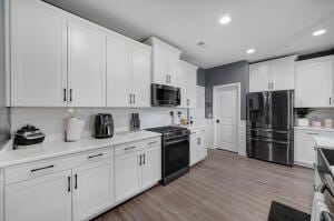 kitchen featuring black appliances, white cabinets, light countertops, and light wood-style floors