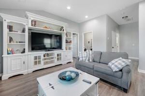 living area featuring vaulted ceiling, recessed lighting, wood finished floors, and baseboards