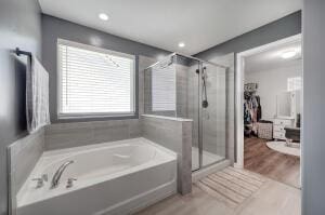 full bath featuring recessed lighting, a bath, wood finished floors, and a stall shower