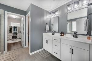 full bath with a sink, wood finished floors, baseboards, and double vanity