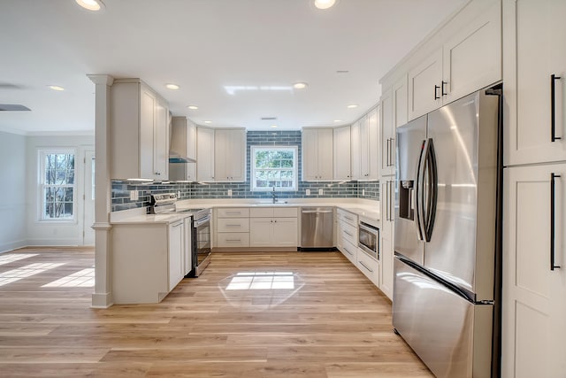 kitchen featuring sink, appliances with stainless steel finishes, white cabinets, decorative backsplash, and light wood-type flooring