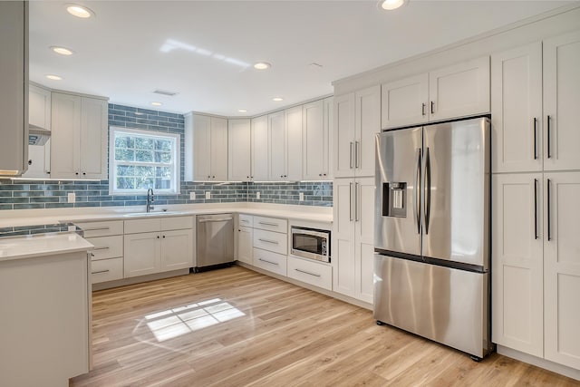 kitchen featuring stainless steel appliances, sink, white cabinets, and light hardwood / wood-style flooring