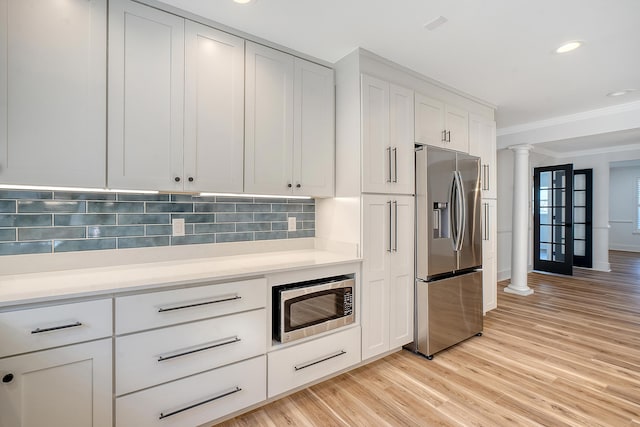 kitchen featuring decorative columns, backsplash, white cabinets, stainless steel appliances, and crown molding