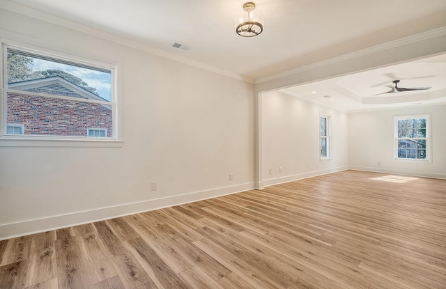 spare room with crown molding, ceiling fan, a tray ceiling, and light wood-type flooring