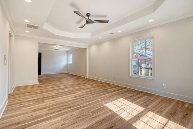 spare room with crown molding, a tray ceiling, ceiling fan, and light wood-type flooring