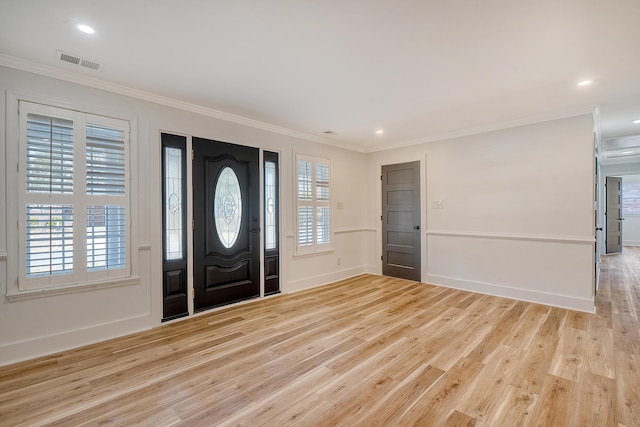 foyer with ornamental molding, a wealth of natural light, and light hardwood / wood-style flooring