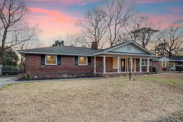 single story home with a porch and a lawn