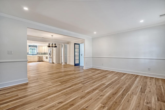 unfurnished living room with light hardwood / wood-style flooring, ornamental molding, and a chandelier