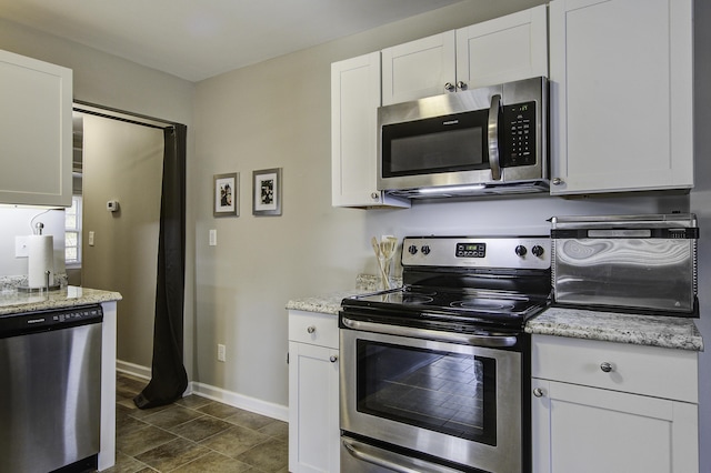 kitchen featuring stainless steel appliances, white cabinetry, and light stone countertops