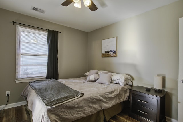 bedroom with ceiling fan, multiple windows, and dark hardwood / wood-style flooring