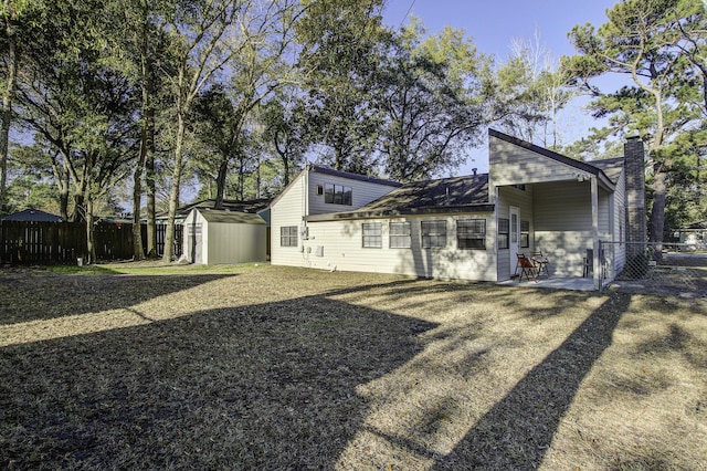 rear view of property featuring a storage unit