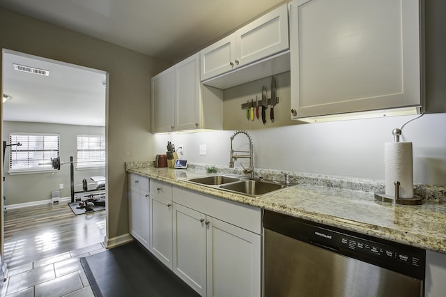 kitchen featuring light stone countertops, sink, white cabinets, and dishwasher