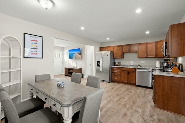 kitchen featuring stainless steel appliances, light hardwood / wood-style flooring, and light stone counters