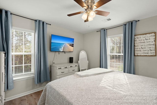 bedroom with hardwood / wood-style flooring, ceiling fan, and multiple windows