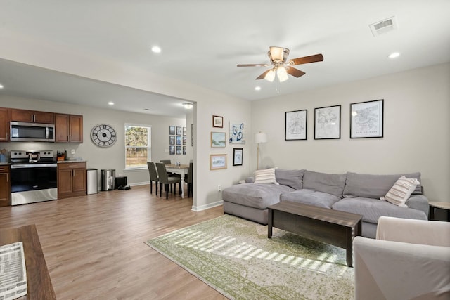 living room with light hardwood / wood-style flooring and ceiling fan