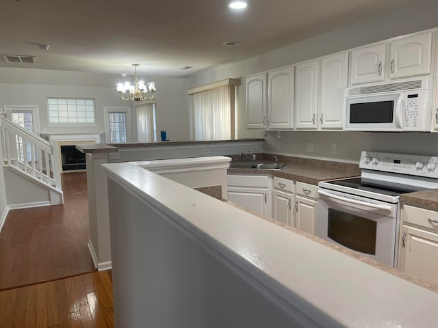 kitchen with pendant lighting, a notable chandelier, white appliances, dark hardwood / wood-style flooring, and white cabinets