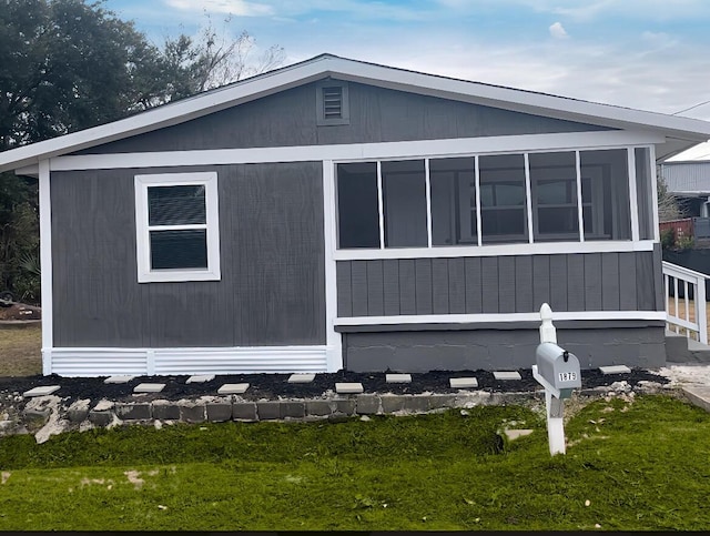 view of property exterior with a sunroom and a yard