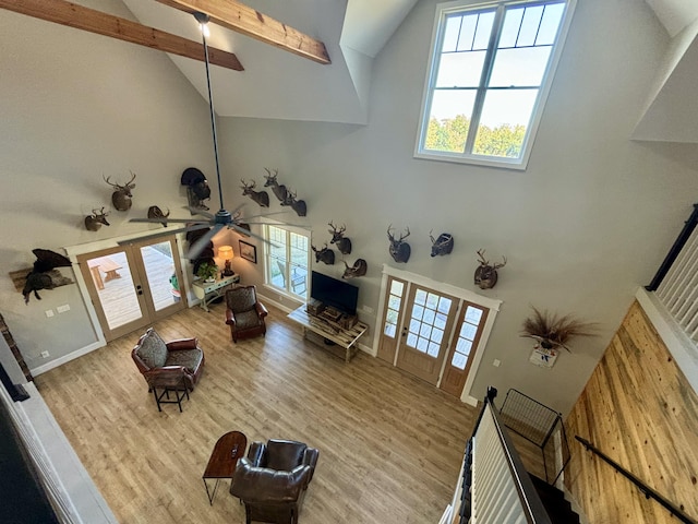 living room with high vaulted ceiling, french doors, ceiling fan, beam ceiling, and light hardwood / wood-style floors