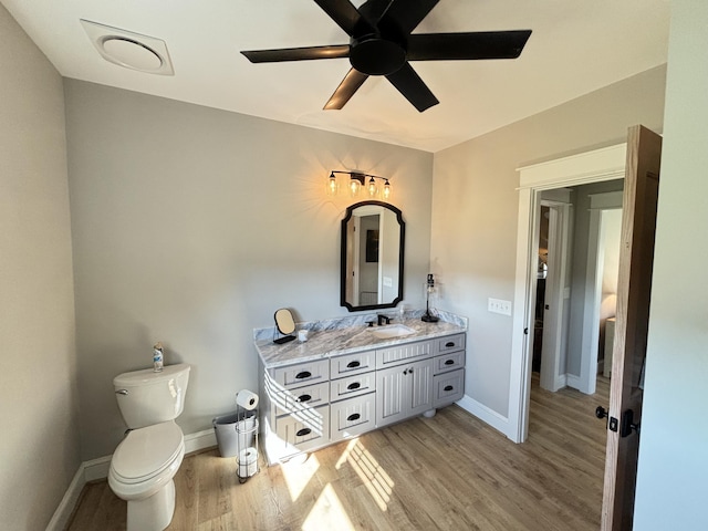 bathroom featuring wood-type flooring, vanity, toilet, and ceiling fan