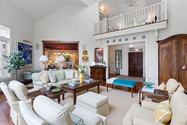 living room with high vaulted ceiling, wood-type flooring, and ceiling fan with notable chandelier