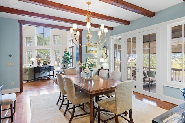 dining room featuring beamed ceiling, wood-type flooring, a chandelier, and french doors