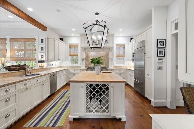 kitchen with sink, white cabinetry, stainless steel appliances, a kitchen island, and wood counters