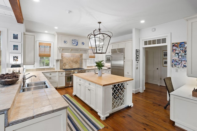 kitchen featuring white cabinetry, sink, hanging light fixtures, a center island, and built in appliances