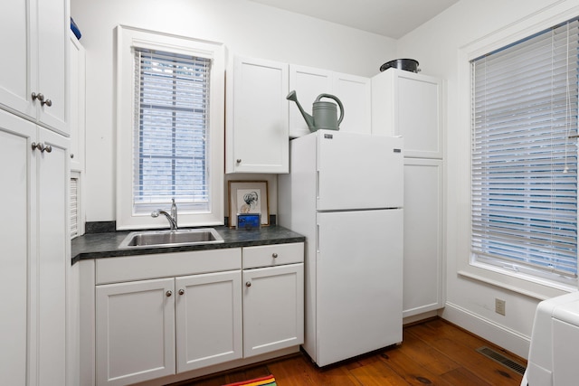 kitchen with white refrigerator, dark wood-type flooring, sink, and white cabinets