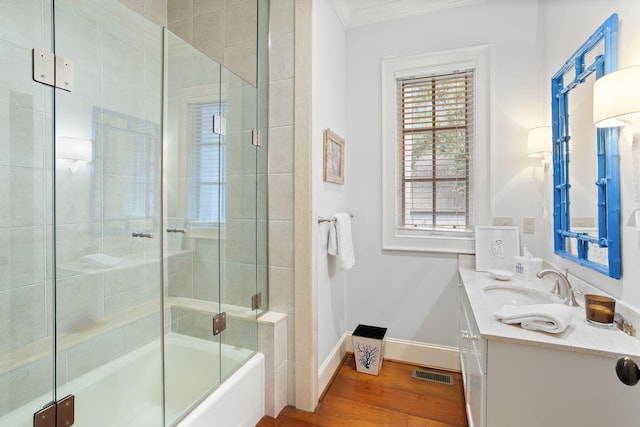 bathroom with ornamental molding, combined bath / shower with glass door, hardwood / wood-style floors, and vanity