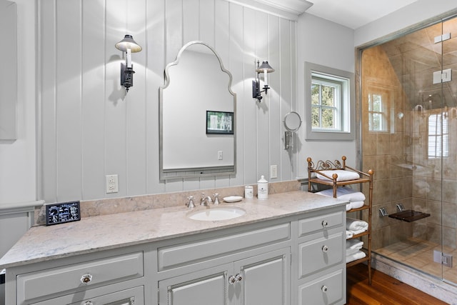 bathroom with hardwood / wood-style flooring, vanity, and walk in shower