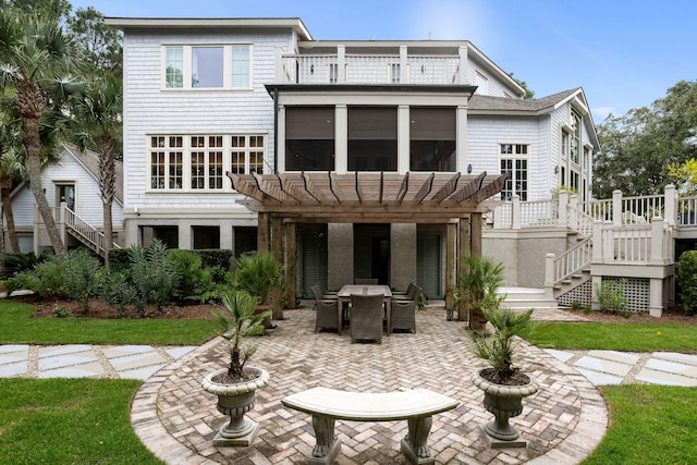 rear view of property featuring a pergola, a sunroom, a patio, and a balcony