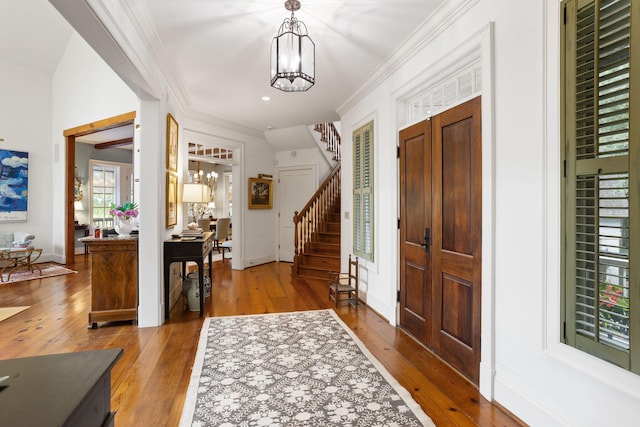 entryway featuring crown molding, hardwood / wood-style floors, and a notable chandelier