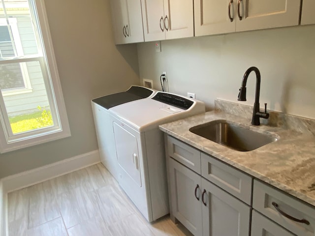 laundry area featuring sink, washer and dryer, and cabinets