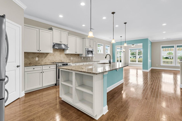 kitchen featuring hanging light fixtures, an island with sink, stainless steel appliances, and white cabinets