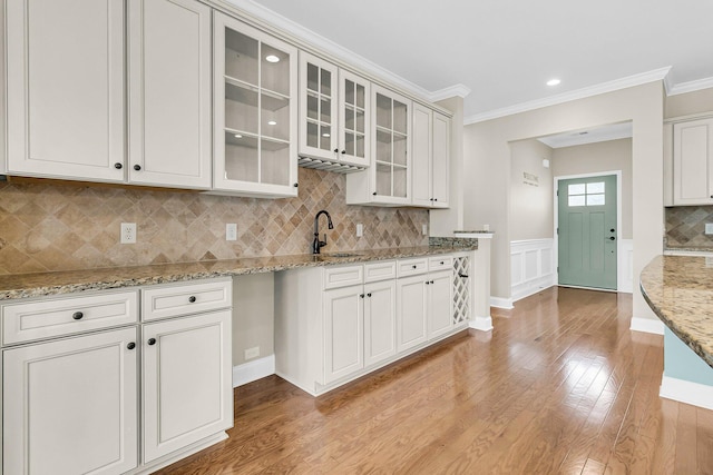 kitchen featuring white cabinets, light stone countertops, crown molding, and light hardwood / wood-style floors