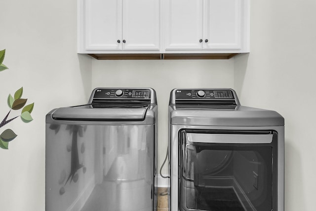 laundry area with washing machine and clothes dryer and cabinets