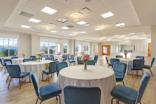 dining space with light hardwood / wood-style flooring, a raised ceiling, and a paneled ceiling