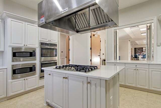 kitchen with range hood, stainless steel appliances, white cabinetry, and a center island