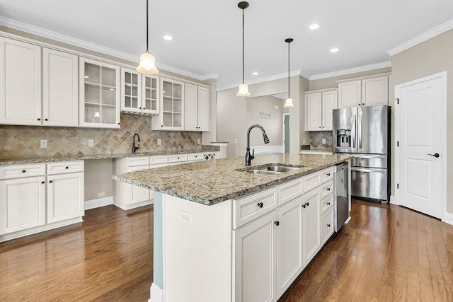 kitchen with appliances with stainless steel finishes, decorative light fixtures, dark hardwood / wood-style floors, a center island with sink, and sink