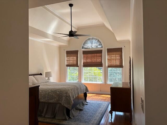 bedroom with ornamental molding, a ceiling fan, vaulted ceiling, and wood finished floors