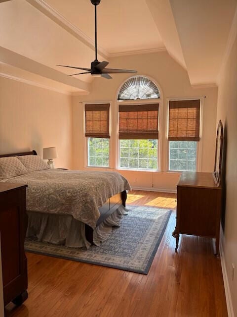 bedroom with ceiling fan, wood finished floors, baseboards, lofted ceiling, and ornamental molding