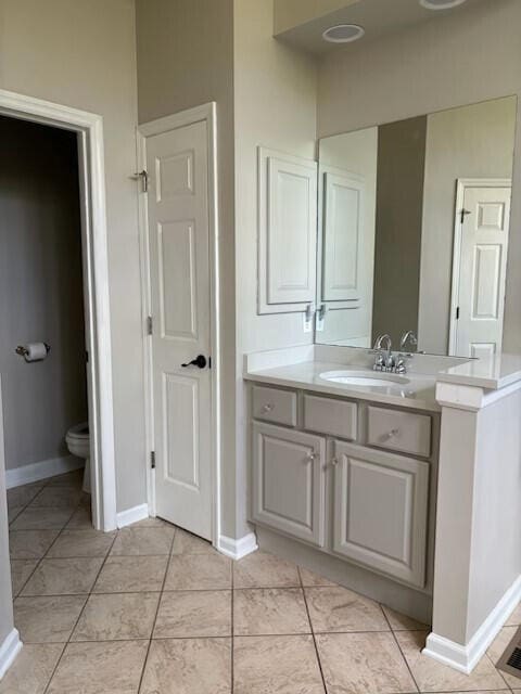 bathroom with vanity, tile patterned flooring, baseboards, and toilet