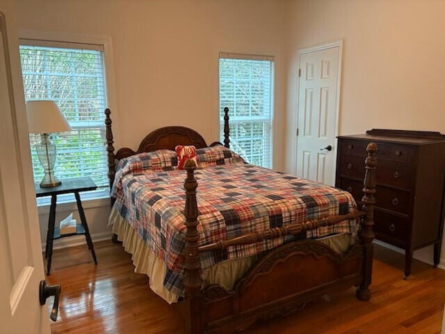 bedroom with baseboards, wood finished floors, and multiple windows