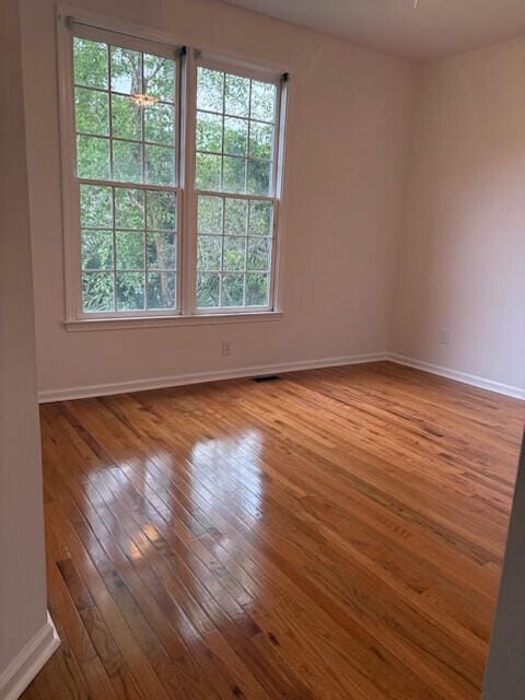 unfurnished room with baseboards, hardwood / wood-style flooring, and visible vents