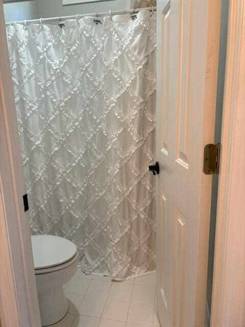 full bathroom featuring tile patterned flooring, curtained shower, and toilet