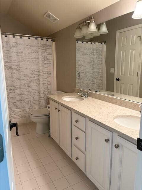 bathroom featuring double vanity, visible vents, a sink, tile patterned floors, and toilet