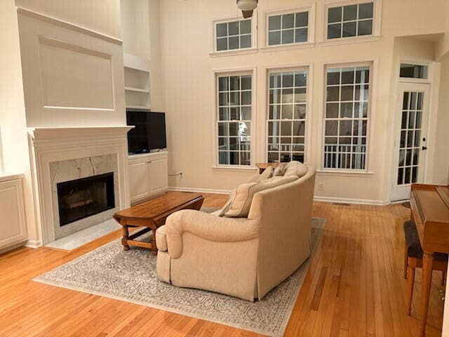 living area featuring a towering ceiling, light wood-style flooring, and a premium fireplace
