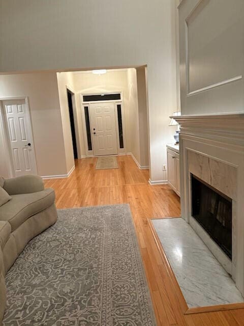 living room with baseboards, light wood-style flooring, and a premium fireplace