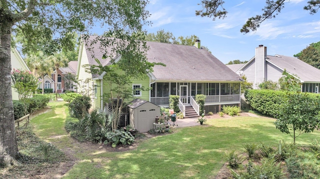 back of property featuring a sunroom, a storage shed, and a lawn